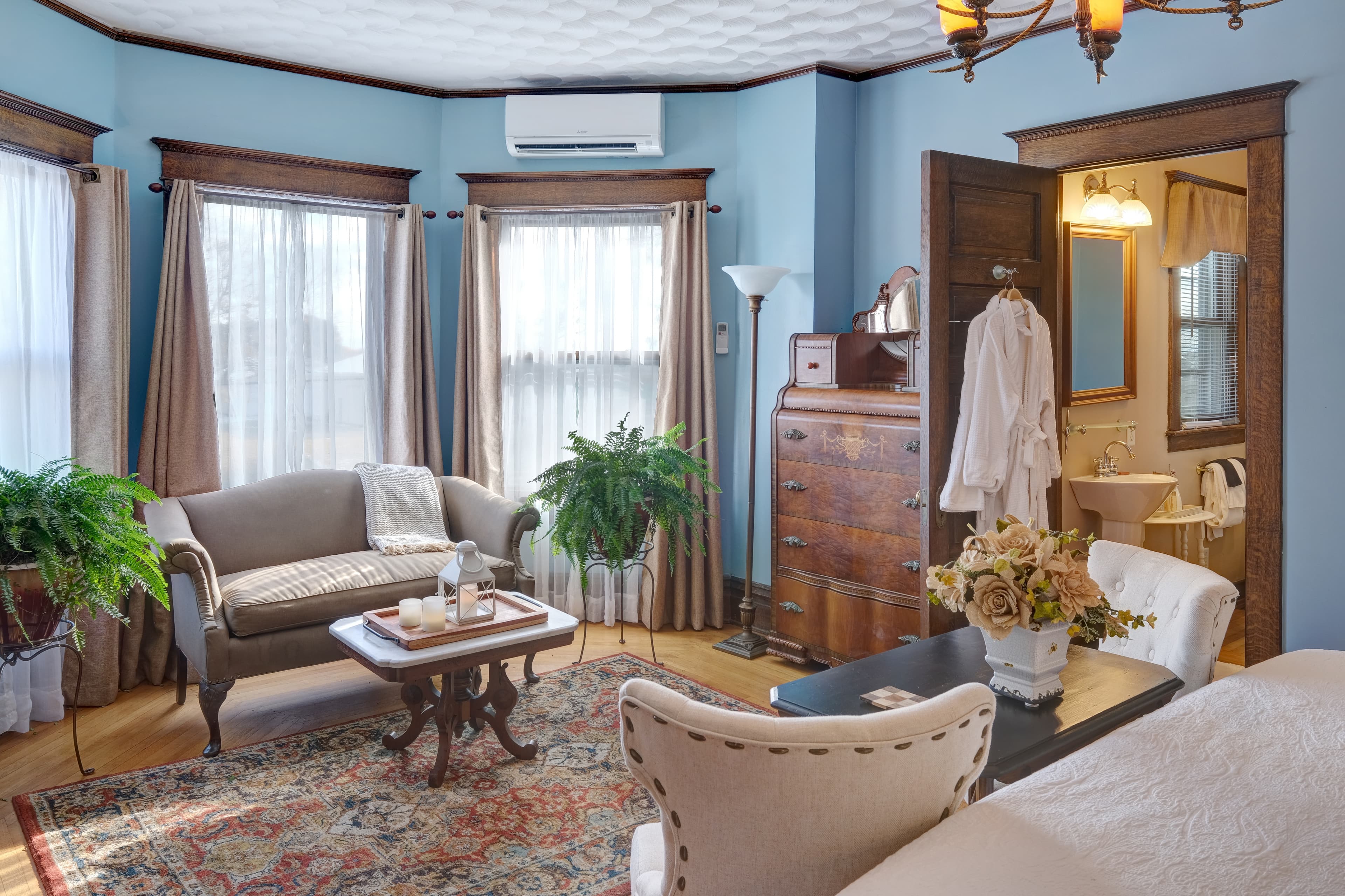 Large seating area with couch and coffee table, patterned oak floors, and antique furniture