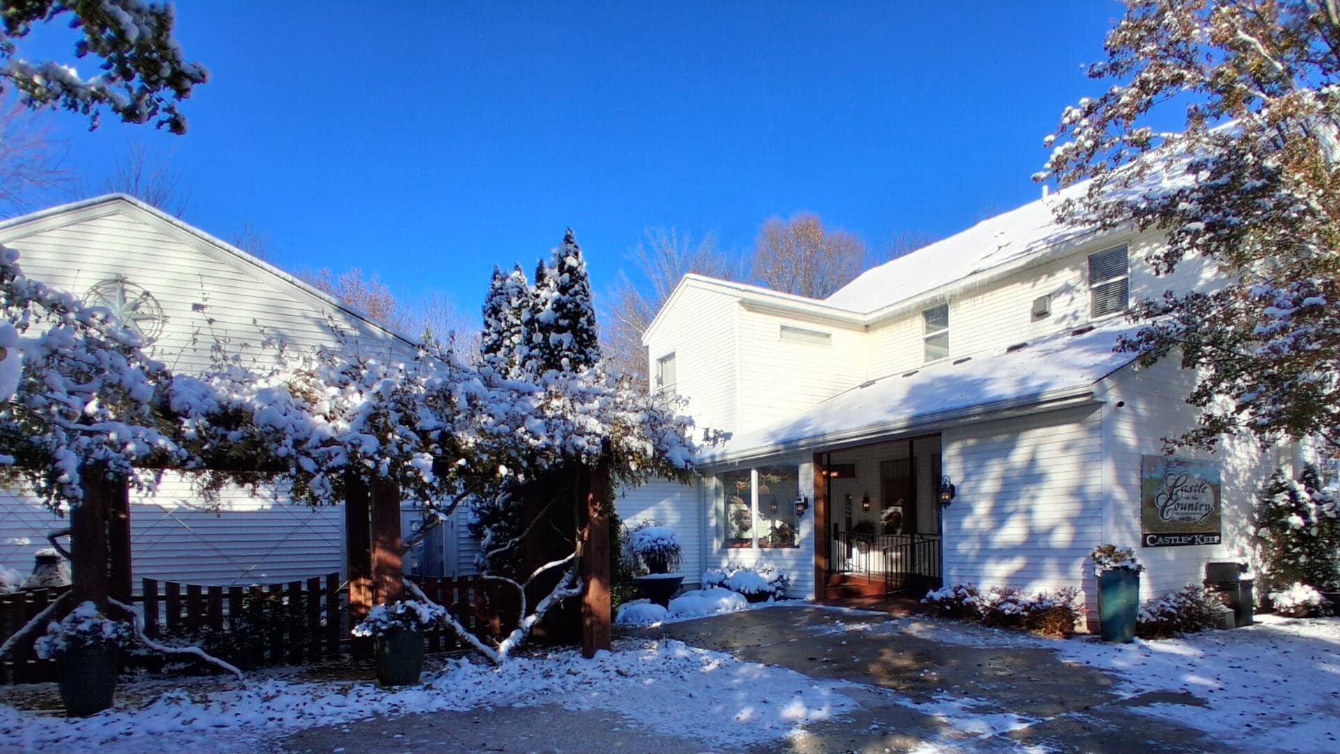 A charming white house covered in snow under a clear blue sky.