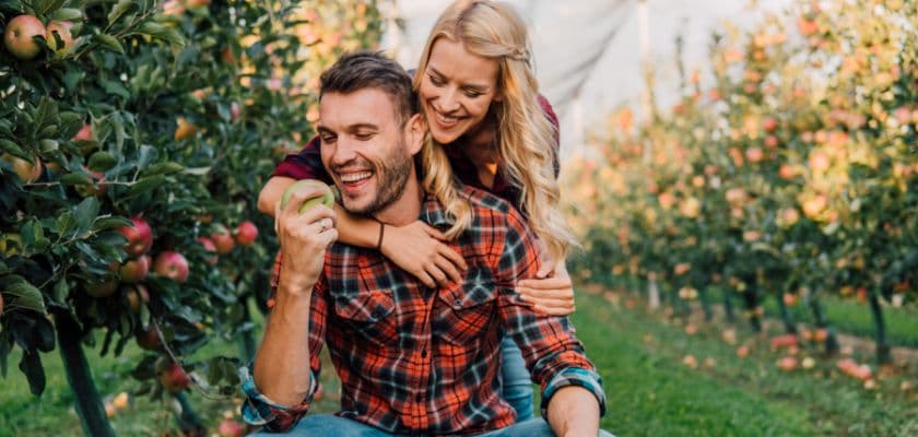 A happy couple enjoys a moment together in an apple orchard.