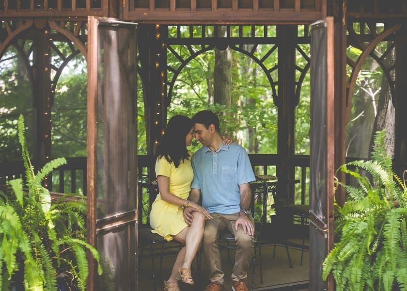 Couple seated together in the gazebo at Castle in the Country, surrounded by greenery and ferns. Couple seated together in the gazebo at Castle in the Country, surrounded by greenery and ferns.