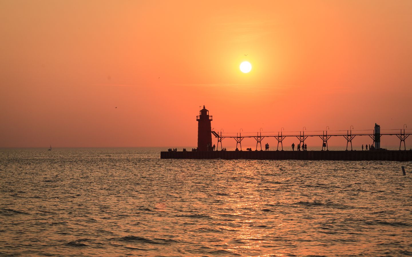 a vibrant orange-red sunset at south pier lighthouse in south haven michigan