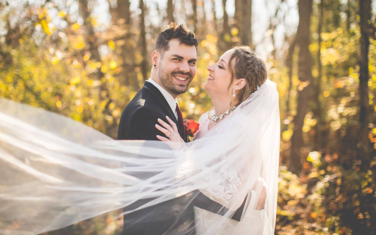 wedding couple at the castle during fall. long bridal veil is sweeping across the scene.