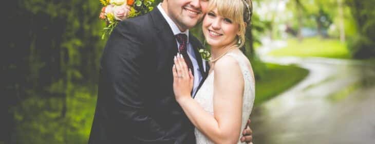 a wedding couple are smiling at the camera on the driveway at castle in the country