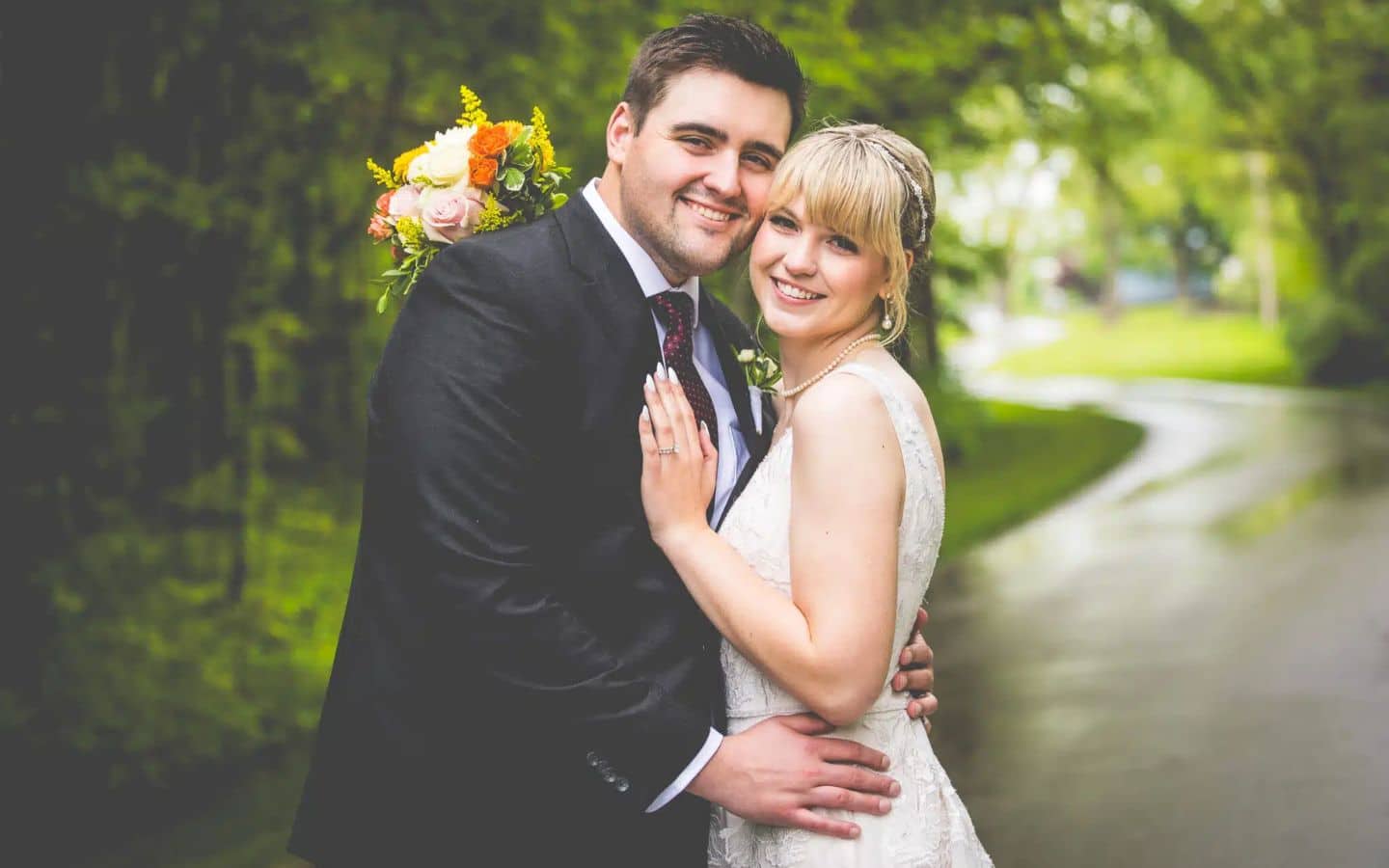 a wedding couple are smiling at the camera on the driveway at castle in the country