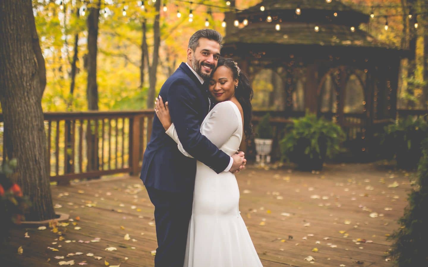 wedding couple at castle in the country embrace in front of the gazebo during fall