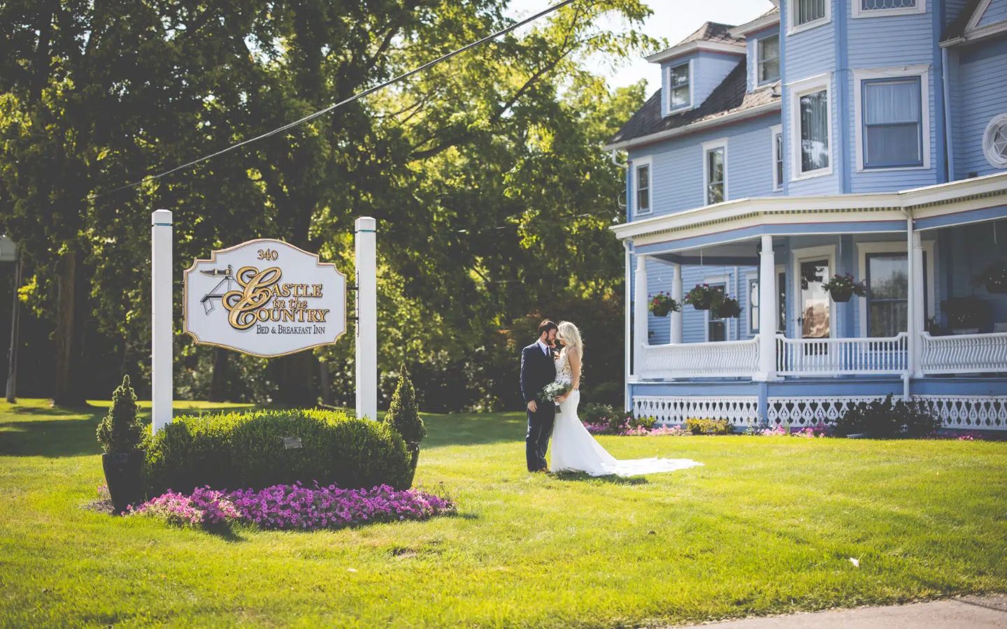 wedding couple pose by the sign in front of castle in the country